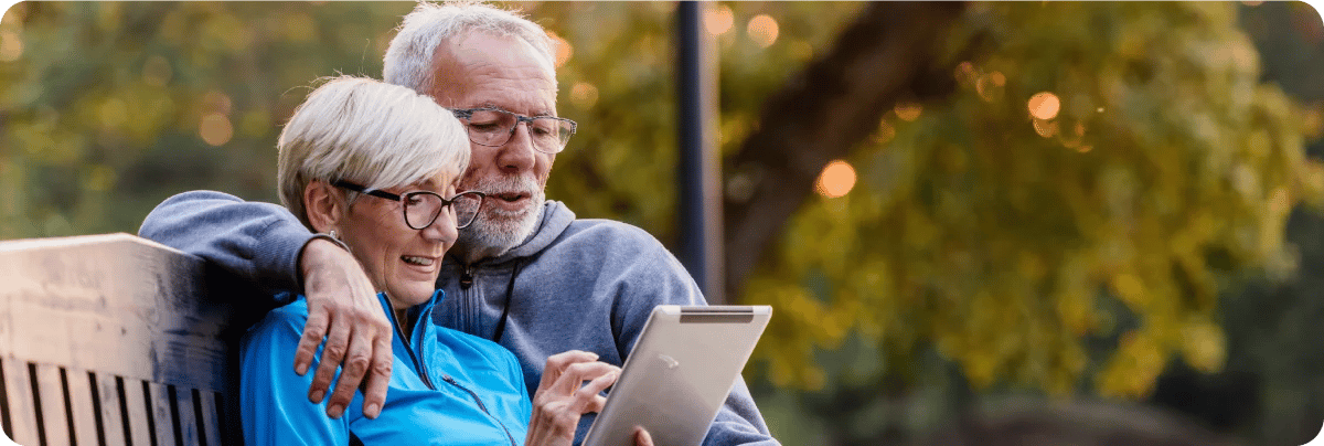Older couple happy sitting in gardens of their retirement village